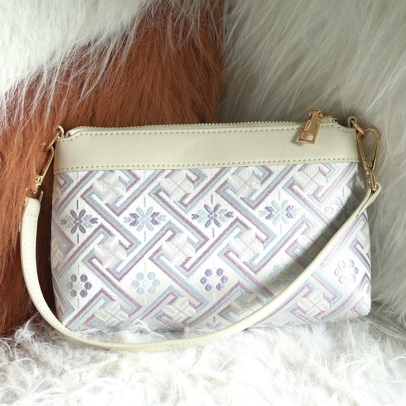 Silver lavender Wanjie brocade-inspired crossbody bag front view on soft neutral texture