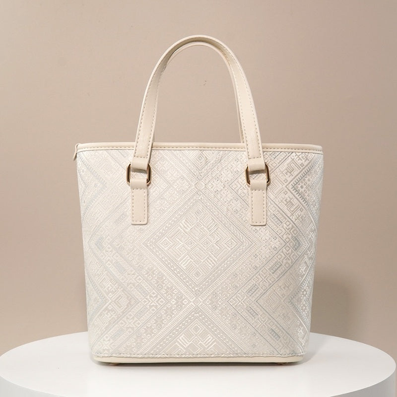 Ivory white geometric brocade-inspired mini tote bag on warm neutral background