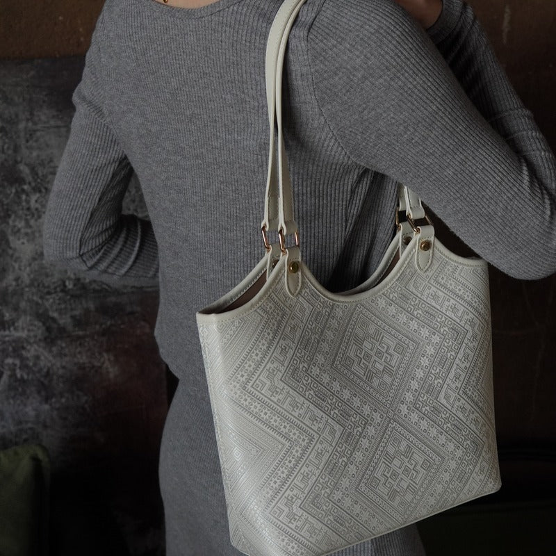 Model carrying ivory white brocade tote bag